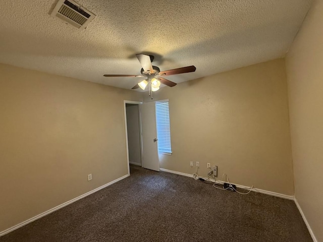 spare room featuring dark colored carpet, visible vents, baseboards, and ceiling fan