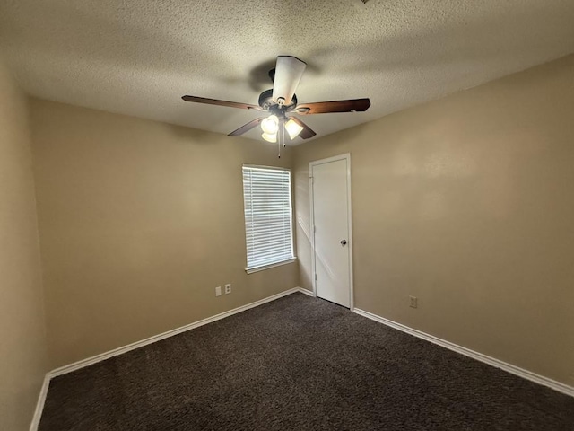 unfurnished room with a ceiling fan, baseboards, dark colored carpet, and a textured ceiling