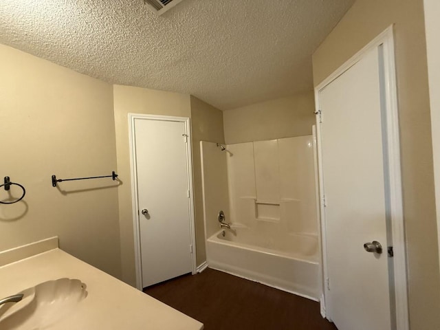 full bathroom with a textured ceiling,  shower combination, and wood finished floors