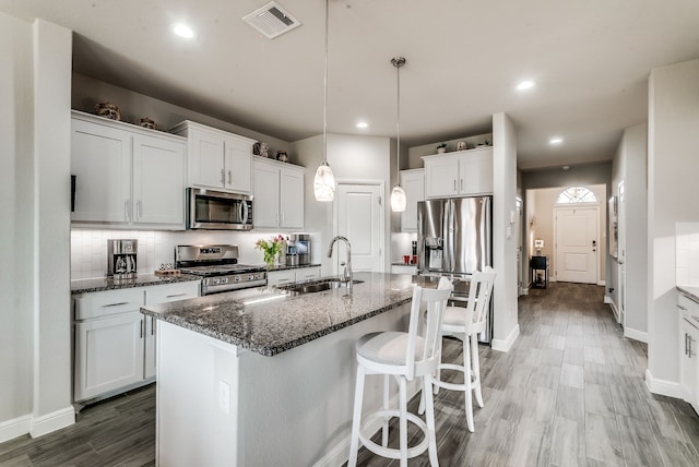 kitchen with tasteful backsplash, visible vents, a breakfast bar, appliances with stainless steel finishes, and a sink