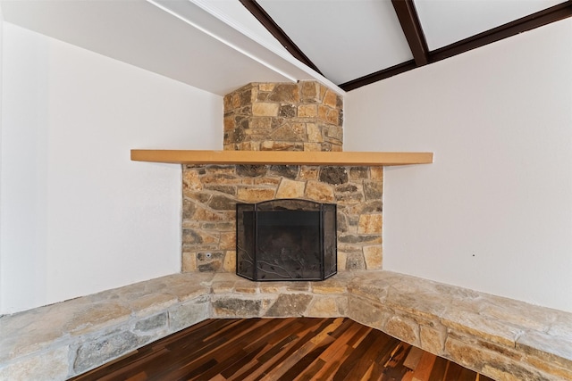 interior details with beamed ceiling, a stone fireplace, and wood finished floors