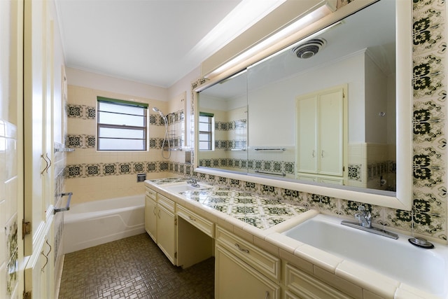 bathroom with tile walls, tub / shower combination, visible vents, and a sink