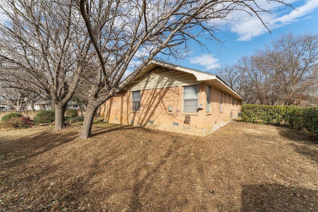 view of side of property with crawl space and brick siding