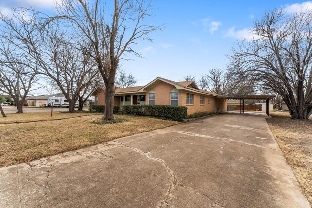 view of front of home with a front lawn, brick siding, concrete driveway, and a carport