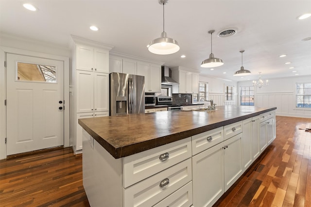 kitchen with visible vents, dark wood-style flooring, stainless steel appliances, wood counters, and wall chimney range hood