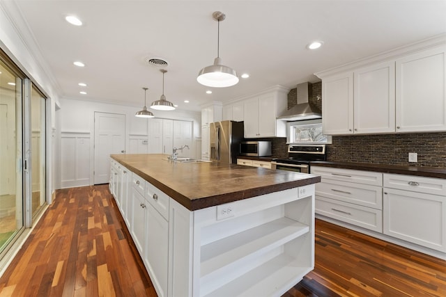 kitchen with tasteful backsplash, visible vents, wall chimney exhaust hood, stainless steel appliances, and wood counters