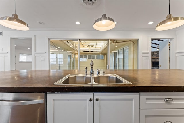 kitchen featuring white cabinetry, ornamental molding, visible vents, and a sink