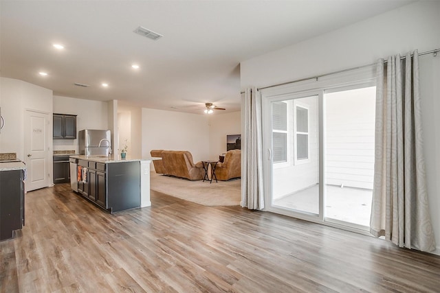 kitchen featuring a ceiling fan, visible vents, light wood finished floors, freestanding refrigerator, and open floor plan