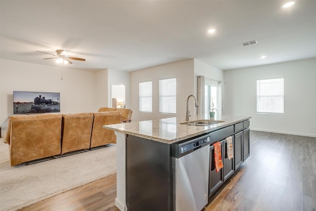 kitchen featuring visible vents, light wood-style flooring, a sink, light stone counters, and stainless steel dishwasher