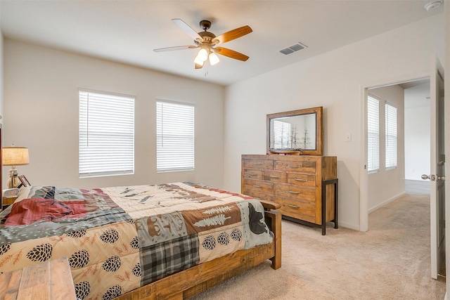 bedroom featuring visible vents, light colored carpet, ceiling fan, and multiple windows