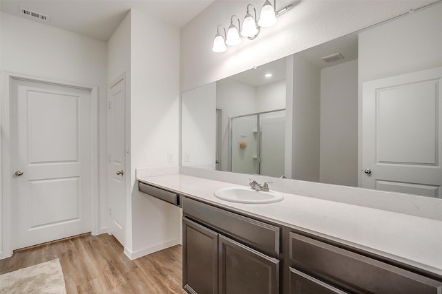 bathroom with visible vents, vanity, wood finished floors, and a shower stall