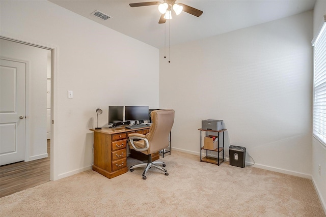 office with visible vents, light colored carpet, baseboards, and ceiling fan