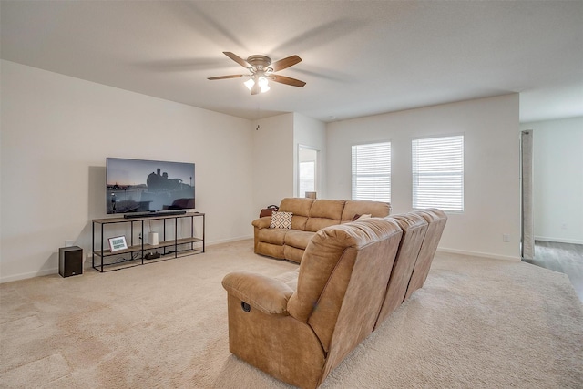 living area featuring carpet flooring, ceiling fan, and baseboards