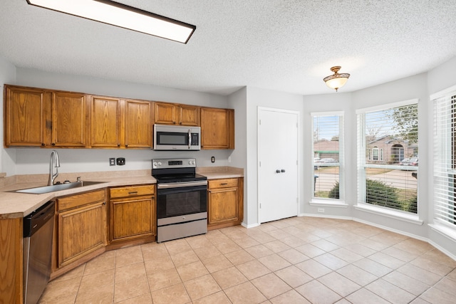 kitchen with a sink, light countertops, brown cabinetry, and stainless steel appliances