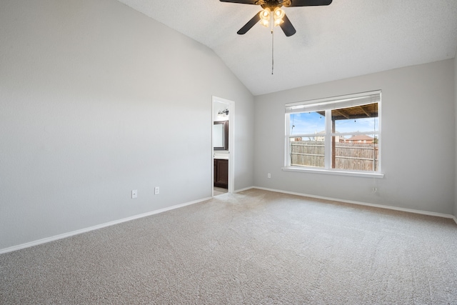 spare room with vaulted ceiling, light colored carpet, baseboards, and ceiling fan