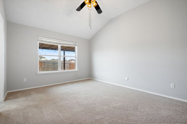 carpeted empty room with a textured ceiling, vaulted ceiling, baseboards, and ceiling fan