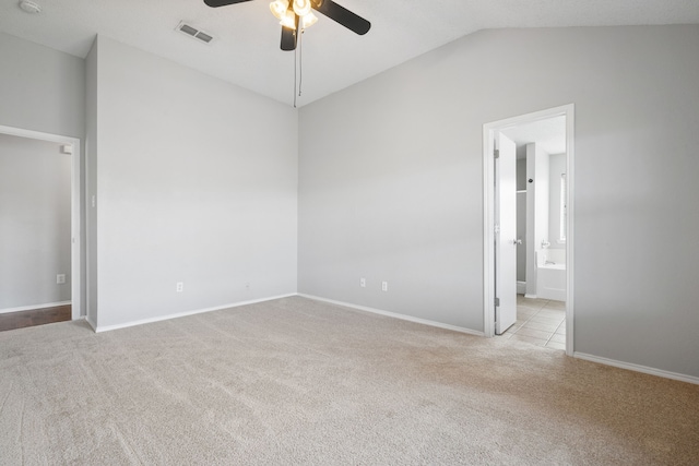 unfurnished bedroom with carpet, visible vents, baseboards, vaulted ceiling, and ensuite bathroom