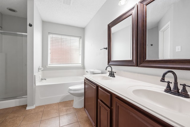 full bathroom featuring tile patterned flooring, a stall shower, a textured ceiling, and a sink