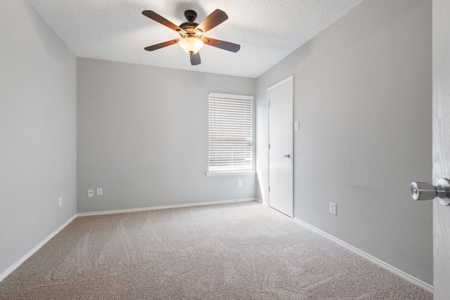 carpeted empty room featuring baseboards, a textured ceiling, and a ceiling fan