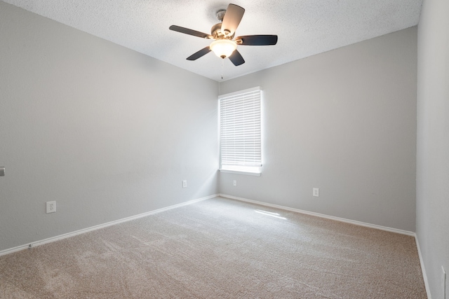 carpeted spare room with a ceiling fan, baseboards, and a textured ceiling