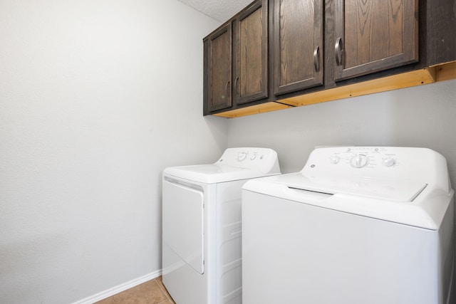 clothes washing area featuring light tile patterned floors, baseboards, cabinet space, and independent washer and dryer