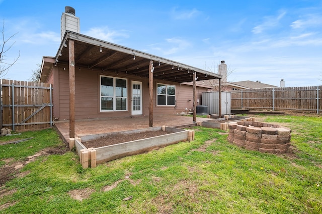 rear view of property featuring central air condition unit, an outbuilding, a patio, a fenced backyard, and a fire pit