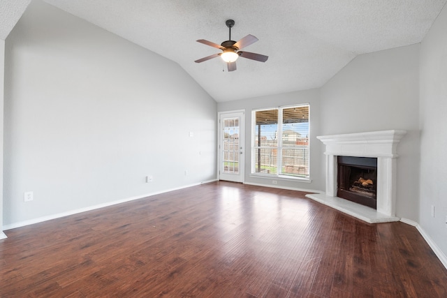 unfurnished living room featuring wood finished floors, a fireplace with raised hearth, ceiling fan, vaulted ceiling, and a textured ceiling