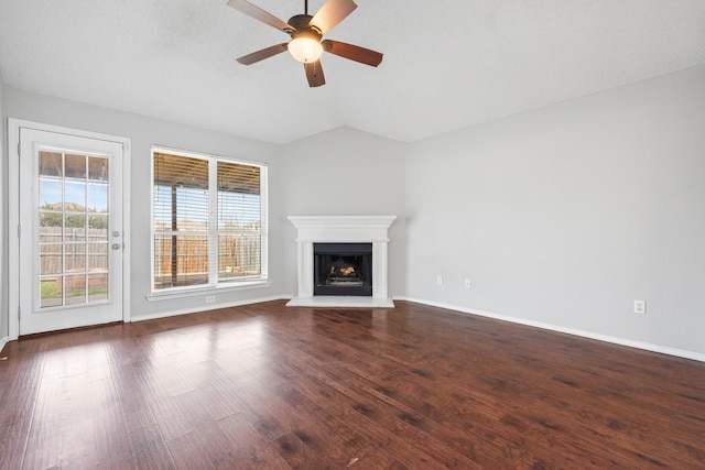 unfurnished living room featuring a fireplace with raised hearth, a ceiling fan, dark wood finished floors, baseboards, and vaulted ceiling