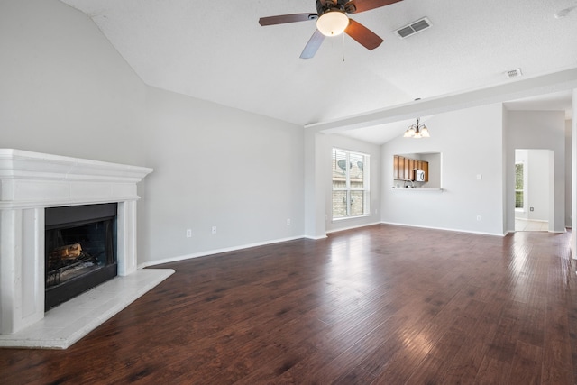 unfurnished living room with wood finished floors, visible vents, a fireplace with raised hearth, vaulted ceiling, and ceiling fan with notable chandelier