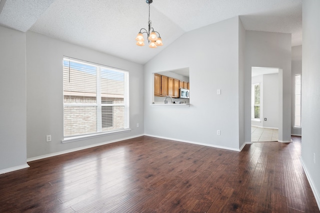 interior space featuring baseboards, dark wood-type flooring, an inviting chandelier, and vaulted ceiling