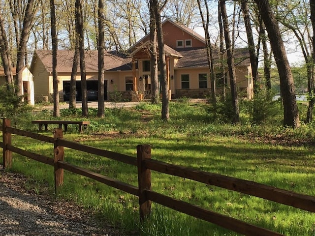 exterior space with a front lawn, fence, and stone siding