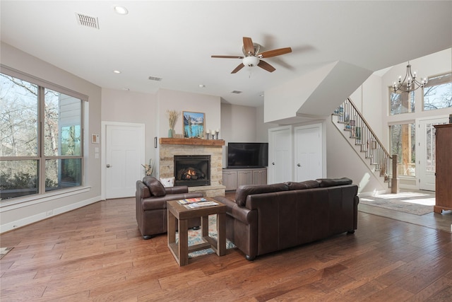 living room featuring stairway, baseboards, visible vents, a fireplace, and light wood-type flooring