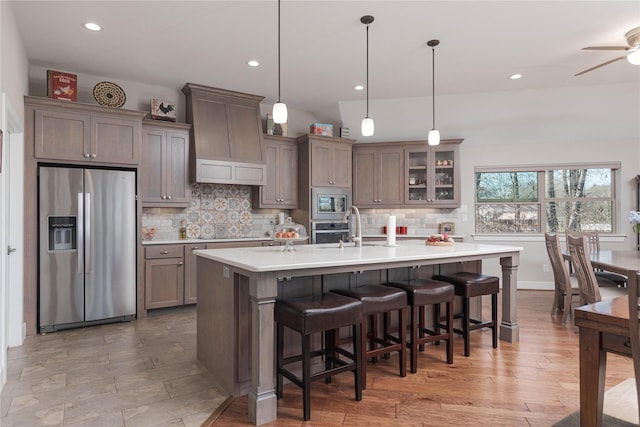 kitchen with premium range hood, a sink, light countertops, appliances with stainless steel finishes, and tasteful backsplash