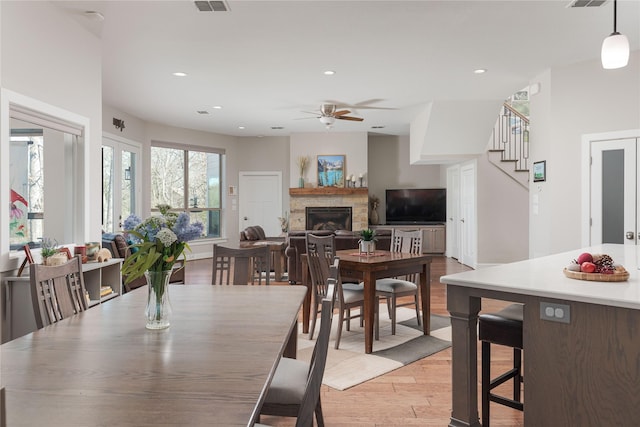 dining room with visible vents, light wood-style flooring, recessed lighting, stairway, and a fireplace