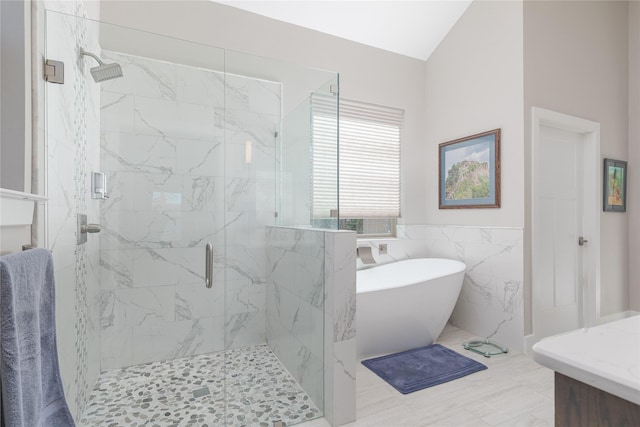 full bath with a marble finish shower, a freestanding tub, tile walls, and a wainscoted wall