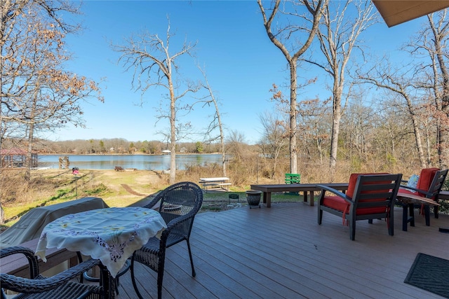 deck with outdoor dining space and a water view