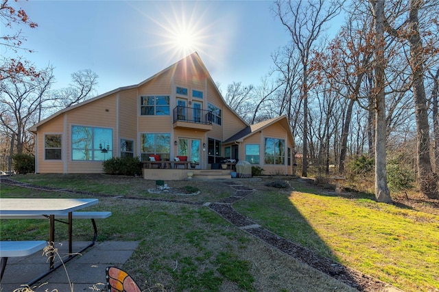 rear view of house with a yard and a balcony