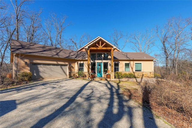 view of front of property featuring aphalt driveway, stone siding, and an attached garage