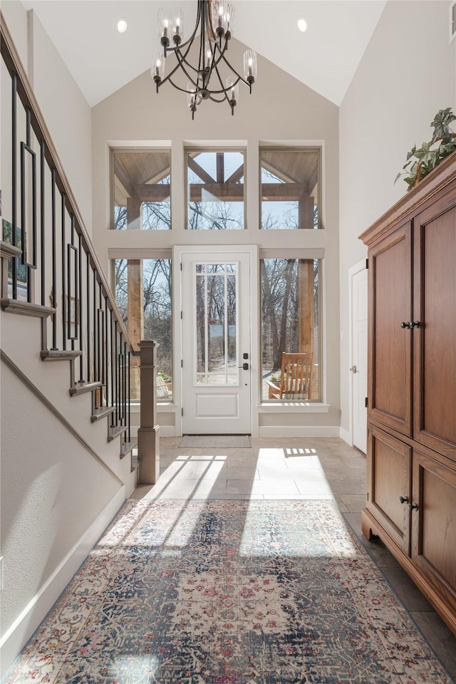 entrance foyer featuring visible vents, high vaulted ceiling, stairway, baseboards, and a chandelier