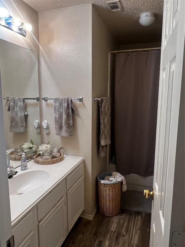 bathroom with vanity, a shower with shower curtain, wood finished floors, visible vents, and a textured ceiling