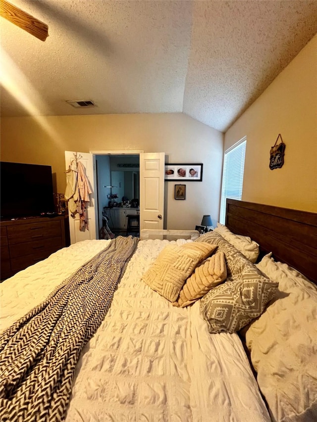 bedroom featuring visible vents, a textured ceiling, a ceiling fan, and vaulted ceiling