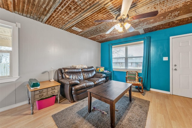 living area featuring visible vents, baseboards, wood finished floors, and a ceiling fan