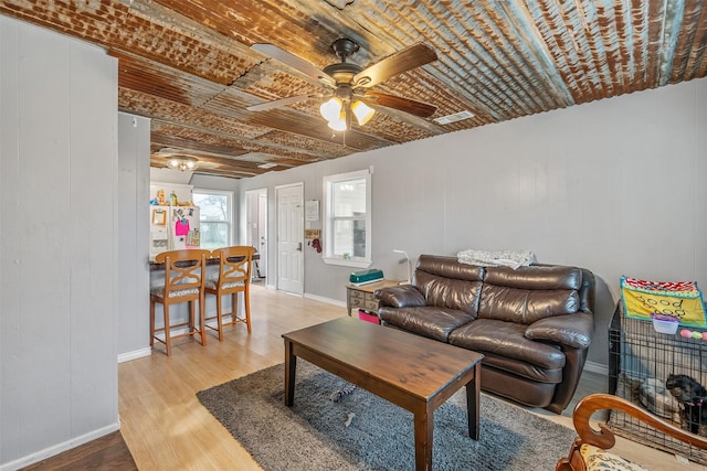 living area featuring light wood-type flooring, baseboards, visible vents, and ceiling fan