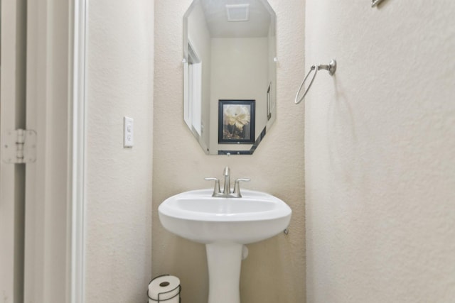 bathroom featuring a sink and a textured wall