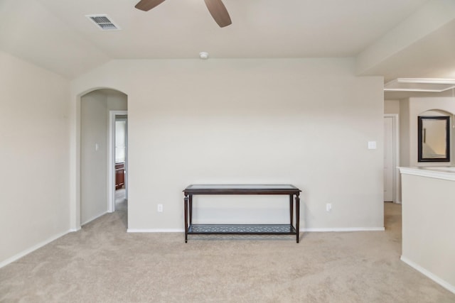 spare room with visible vents, lofted ceiling, carpet flooring, arched walkways, and a ceiling fan