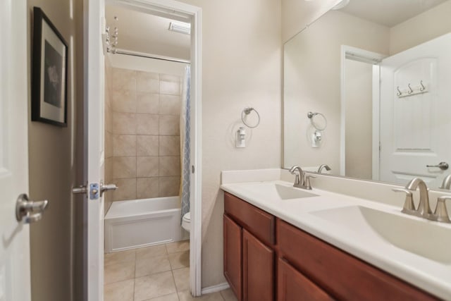 bathroom featuring tile patterned flooring, double vanity, toilet, and a sink