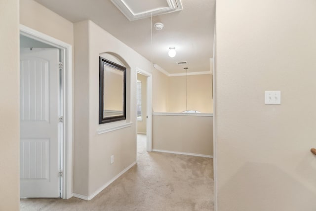 hallway with visible vents, carpet, crown molding, baseboards, and attic access