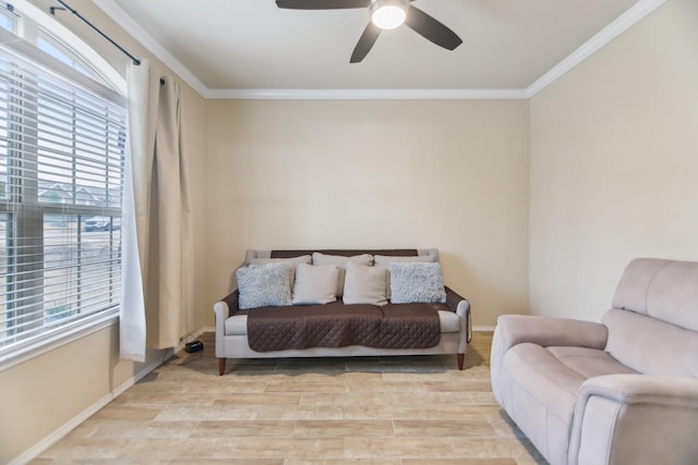 living room featuring light wood-style flooring, a ceiling fan, baseboards, and ornamental molding