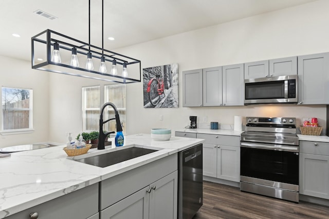 kitchen featuring visible vents, gray cabinets, a sink, dark wood-type flooring, and appliances with stainless steel finishes