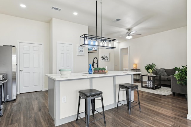 kitchen with ceiling fan, visible vents, a kitchen bar, and dark wood finished floors